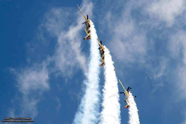 Akrobacje powietrzne wykonywane przez zespół Aerobatic Yakkers podczas Pikniku Lotniczego. W skład zespołu wchodzą trzy samoloty: Su-26 pilotowany przez Jurgisa Kairysa oraz dwa samoloty Jak-52TW pilotowane przez Ioana Postolache oraz Daniela Stefanescu.